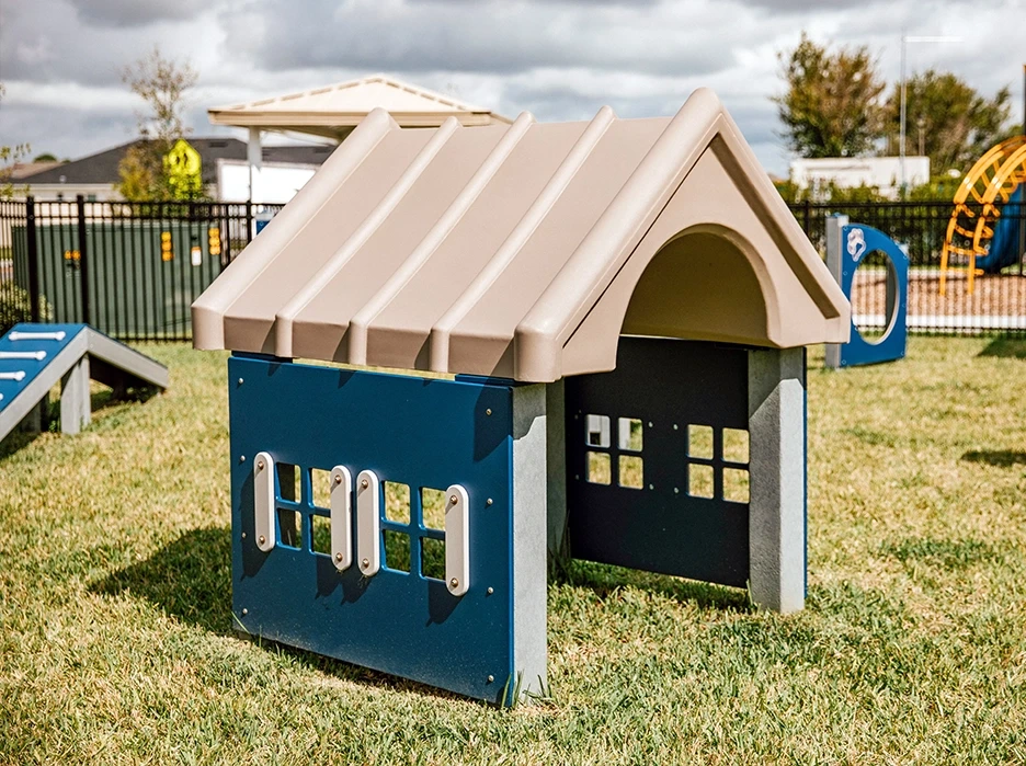 Commercial dog park agility equipment, benches, and amenities in a landscaped community dog park.